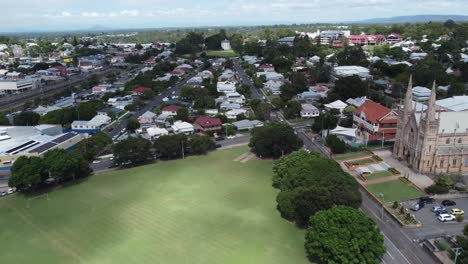 drone flying over a green field towards a residential area and a large catholic church is also visible