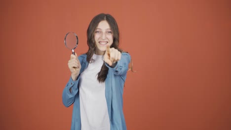 Young-woman-looking-at-camera-with-magnifying-glass.