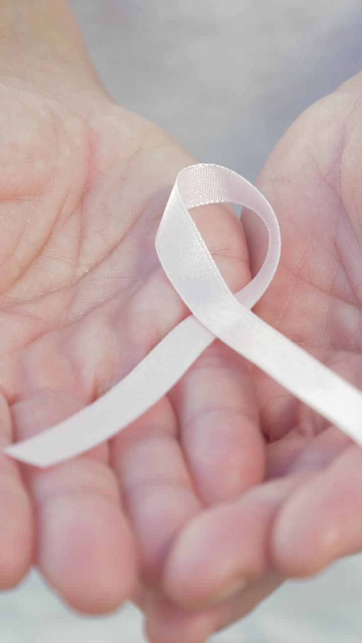 Nastro rosa tenuto in mano per la sensibilizzazione sul cancro