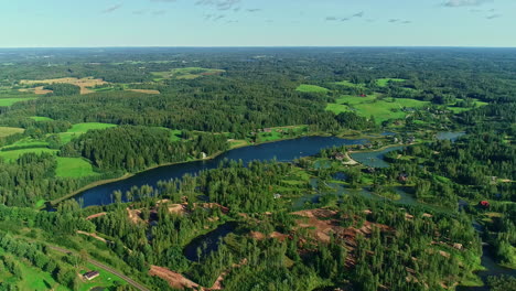 Beautiful-drone-shot-of-a-green-forested-field-with-trees,-lakes-and-nature