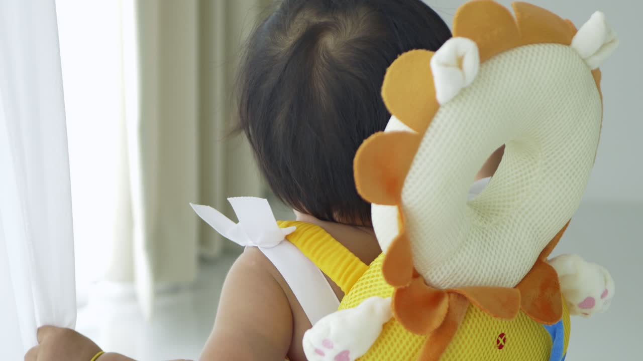A joyful baby girl interacts with her surroundings embodying innocence and care in a cozy home.