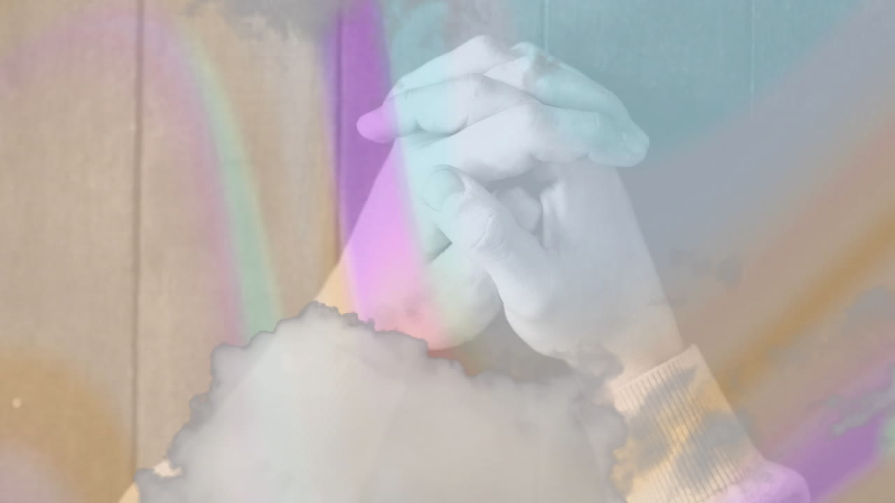Clasping hands over colorful abstract animation with soft hues in background