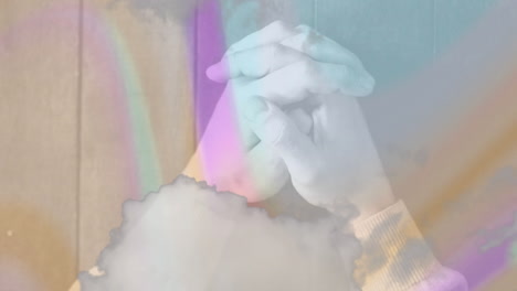 clasping hands over colorful abstract animation with soft hues in background