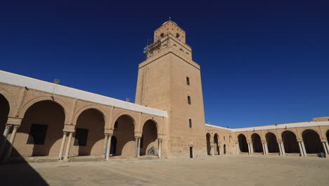 ancient mosque tower and courtyard with roman architecture under clear blue sky in tunisia