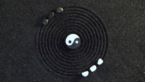 japanese zen-like garden with yin yang stone in sand