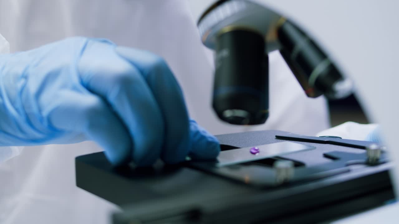 Scientist in Blue Gloves Places Sample Slide on Microscope