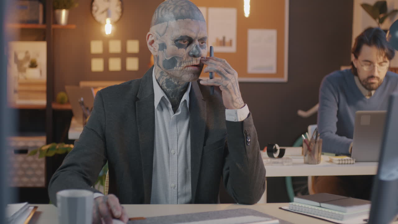 Businessman with Skull Face Paint on Phone Call in Office