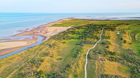 Discover-the-idyllic-charm-of-a-golden-hour-coastal-scene-through-breathtaking-aerial-drone-footage:-estuary,-sandbanks,-ocean,-and-marshlands