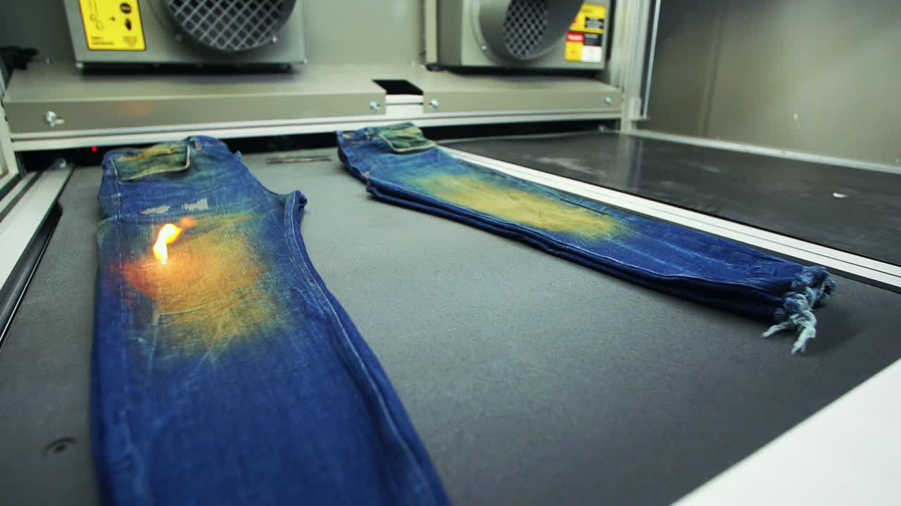 청바지 공장의 데님 레이저 기계는 청바지를 처리합니다.