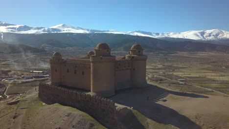 Luftaufnahme-Der-Burg-Von-La-Calahorra-Mit-Sierra-Nevada-Dahinter-In-Granada,-Spanien