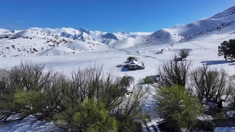 un cobertizo remoto en una granja y un avión no tripulado sobre la línea de árboles revelan increíbles paisajes de invierno en las montañas de nueva zelanda