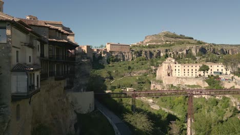 houses hanging next to rocky precipice bridge and church. travelling aerial view of medieval houses next to a cliff. cuenca. spain.