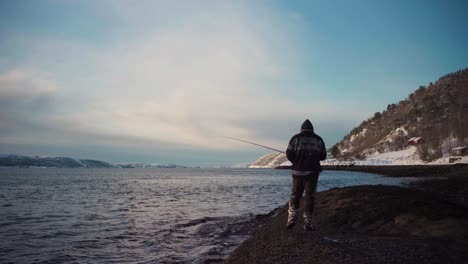 a man is fishing on trondheimsfjorden during sunrise in trøndelag county, norway