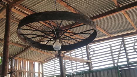 unique rusted old iron wheel used as light fixture in barn