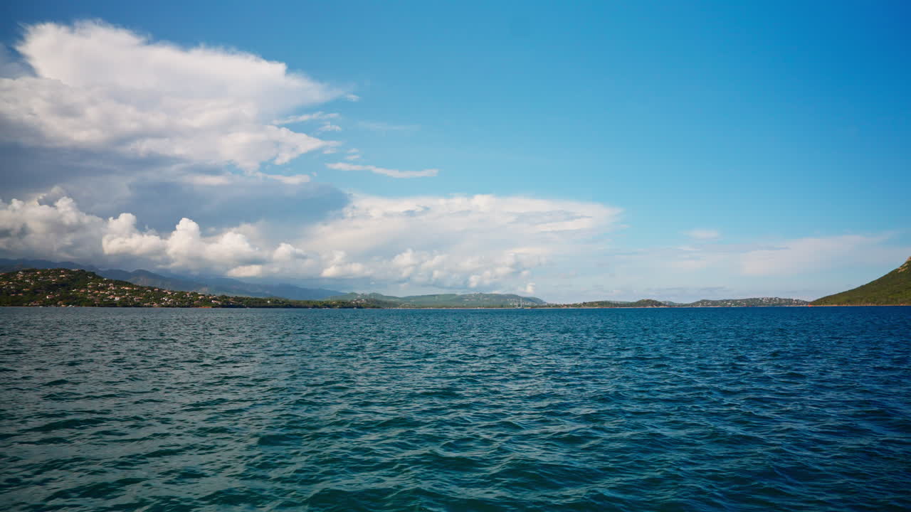 Boat tour along the coastline of Corsica. View of the mediterranean sea. Summer holidays destination. Fluffy clouds in the distance. Island exploration. Peaceful seascape
