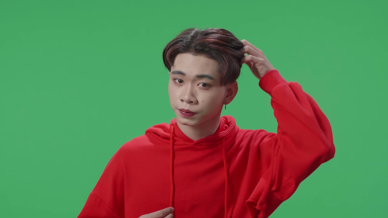 Asian Transgender Male Touching Skin On Her Face While Looking At Camera Like A Mirror On Green Screen In Studio