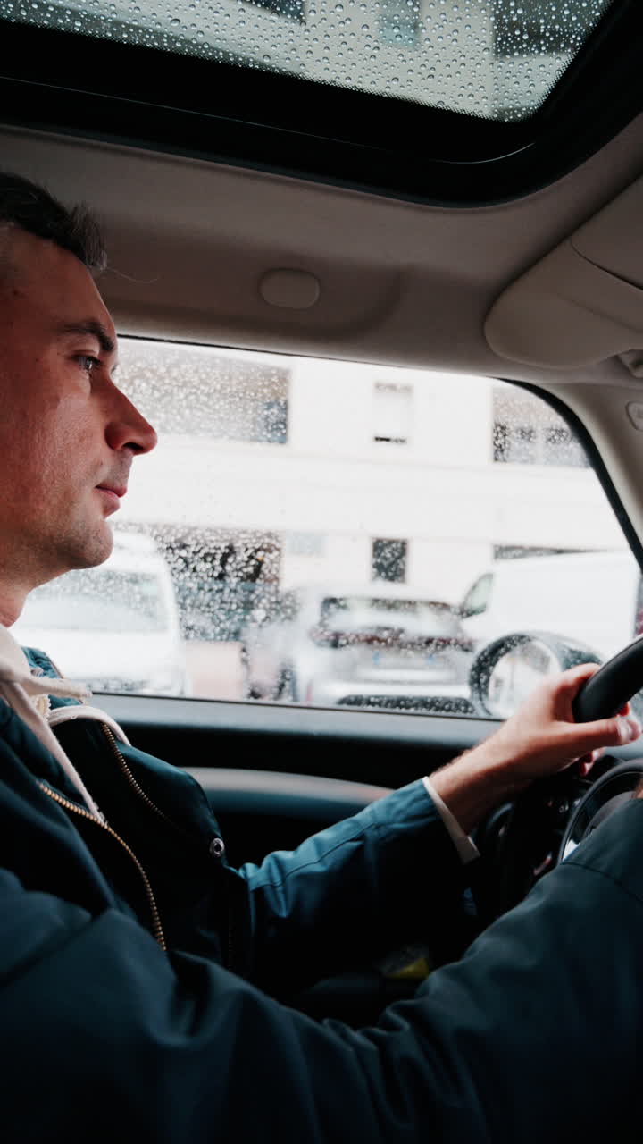 Close up of a man driving a car on the road in the rain