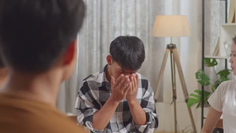 asian teen group sitting and discussing at home. close up of teen students support a boy in plaid shirt not to crying