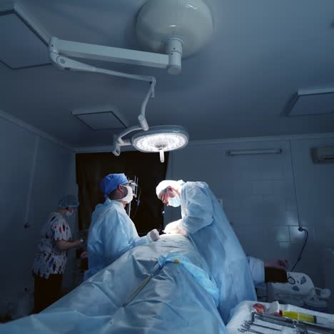 operation in surgical room. team of doctors conduct a surgery to a patient under bright medical lamp. nurse assists surgeons in the operating room.