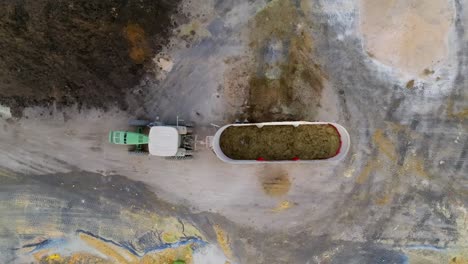 Top-down-Drone-shot-of-Tractor-being-loaded-with-manure