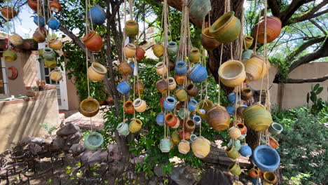 colorful terracotta pots hang from a tree on strings