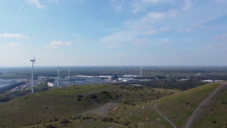 Industrial-buildings-with-wind-turbines-behind-mining-heap-in-Belgium,-aerial-view