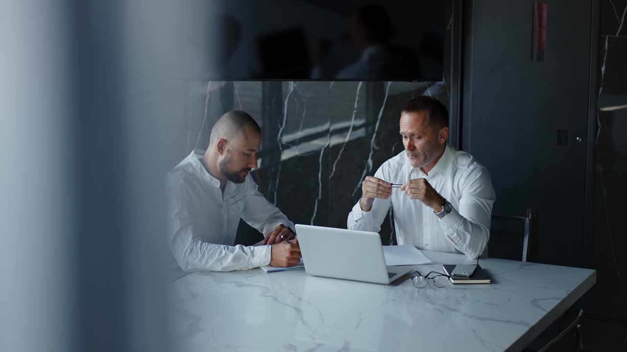 Due uomini d'affari che discutono i dati del mercato finanziario utilizzando un laptop e un tablet. Consulente finanziario, broker, manager.