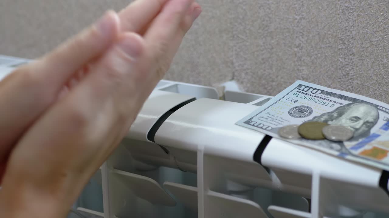 женщина согревает руки на аккумуляторе, нагреватель дома в комнате. 4к. близко. медленное движение