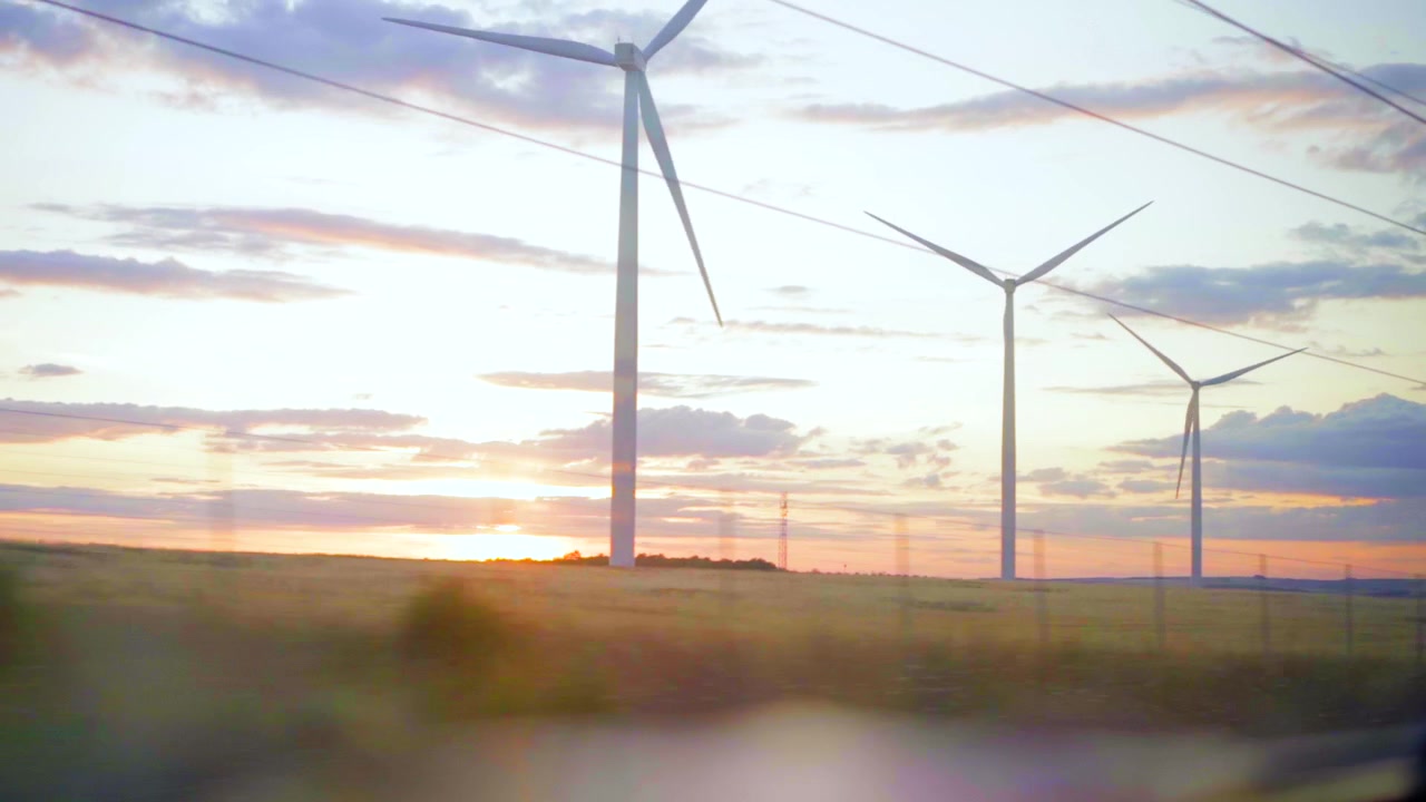 Paesaggio dal finestrino del treno al tramonto, vista della campagna con turbina eolica