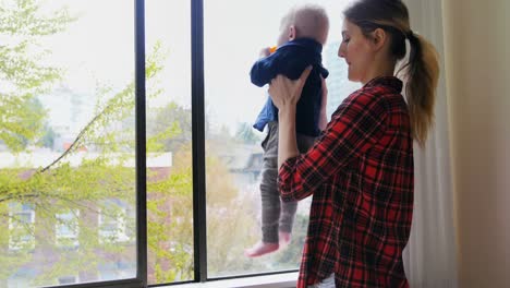 mother with her baby standing near window 4k