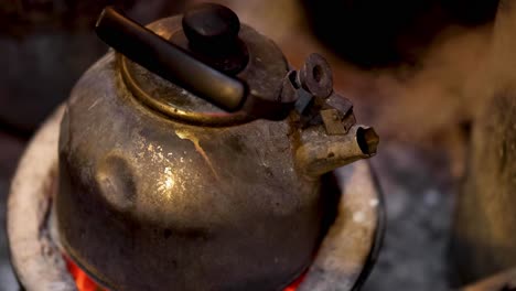 una tetera vieja humeando en una estufa de carbón brillante