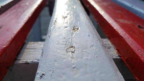 close up macro shot of an old outdoor wooden bench painted in white and red in the part at sunset