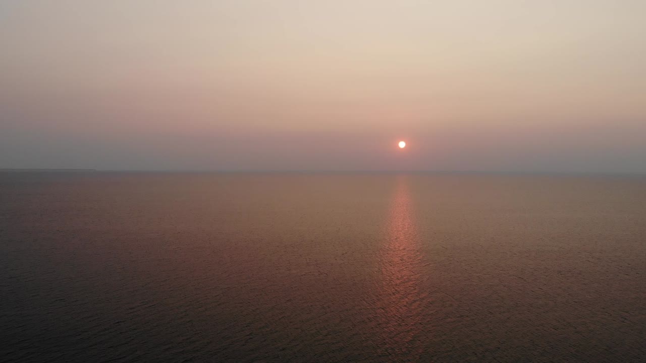 위스콘신주 도어 카운티에 있는 엘리슨 블러프 주립 공원에서 시원한 여름 밤 멋진 일몰을 포착하는 두 소나무 사이를 지나가는 드론 샷