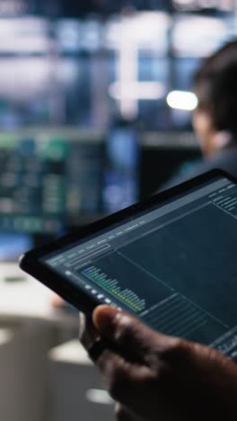 vertical video close up of data center software developer using tablet to review code