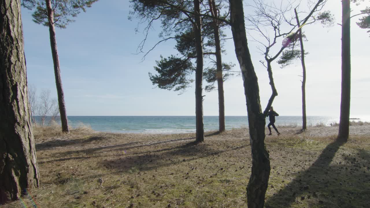 mujer trotando entre árboles junto a la playa en un día cálido y soleado