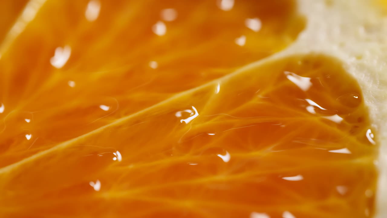 Segmento d'arancia macro con succo luccicante, primo piano che rivela polpa traslucida, goccioline scintillanti, fresco e vivace.