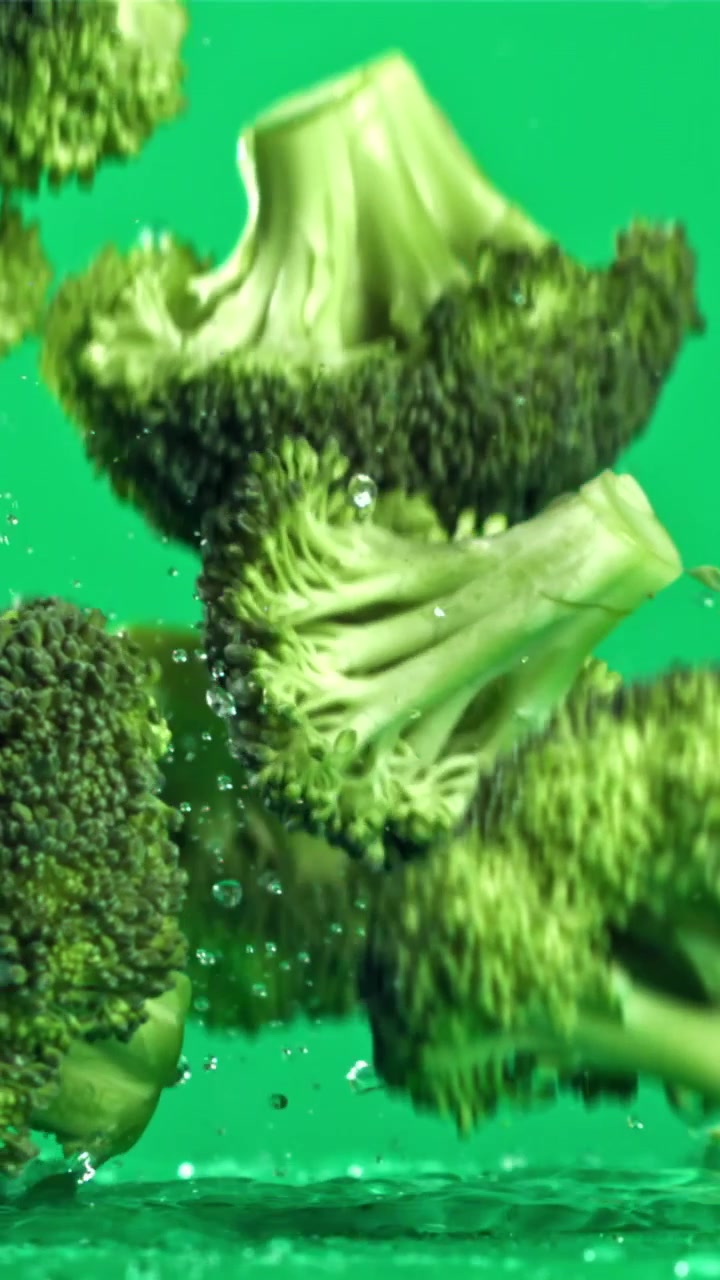 Cimette di broccoli freschi che cadono nell'acqua al rallentatore.