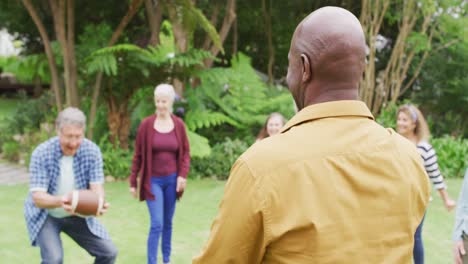 animation of happy diverse female and male senior friends playing american football in garden