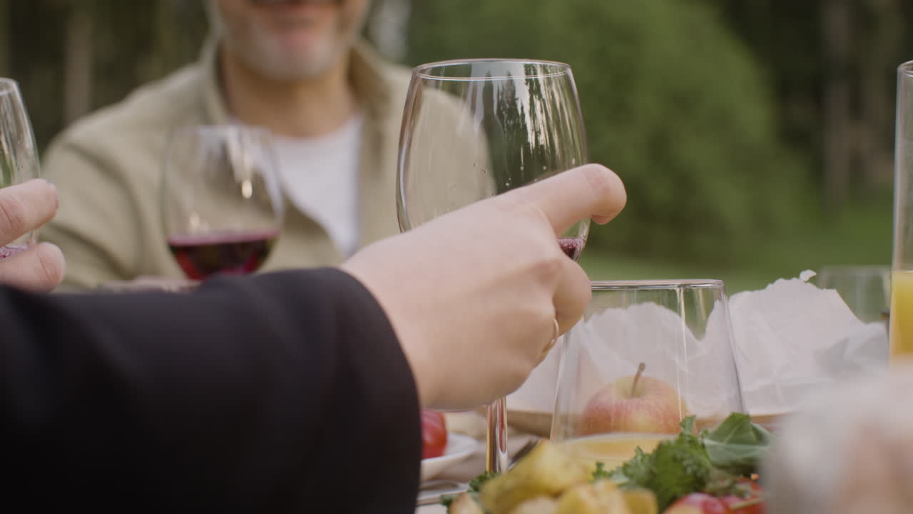 남자 손 공원에서 야외 파티 동안 테이블에 와인 한 잔을 넣어