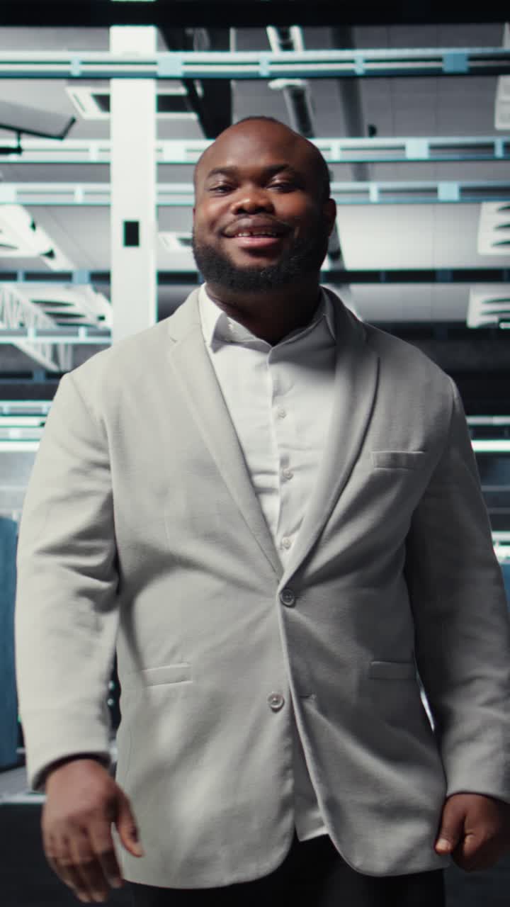 Vertical video Smiling manager in data center doing checkup on hardware to avoid downtime