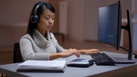 a woman wearing headphones working on a computer at a desk