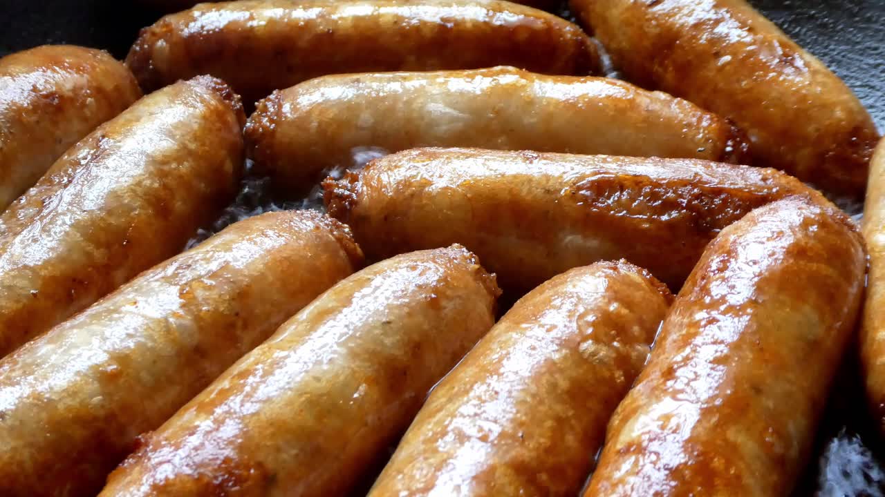salchichas freír en sartén caliente cocinar deliciosa carne a la parrilla dorada chisporroteando vista superior de cerca