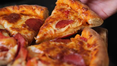 close up of a hand reaching in to grab a mouth-watering piece of pizza