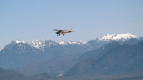 Single-Engine-Airplane-Flying-With-Snow-Capped-Mountains-Backdrop