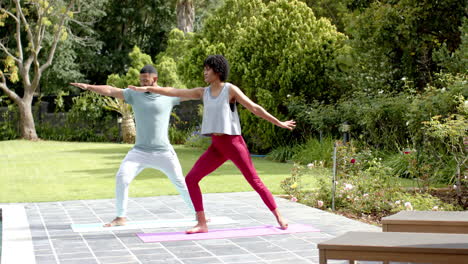 una pareja afroamericana enfocada practicando yoga de pie en el jardín, copia el espacio, cámara lenta