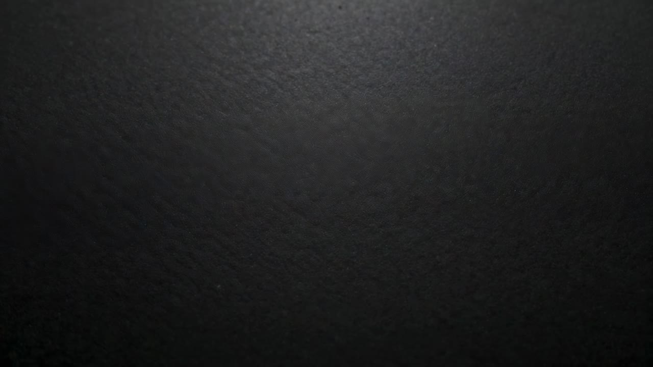 Showing dark coarse textured surface in closeup while light rising, revealing diffuse top highlight