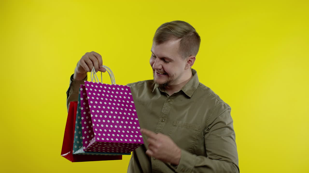 hombre levantando bolsas de compras, pareciendo satisfecho con la compra, disfrutando de descuentos en el viernes negro
