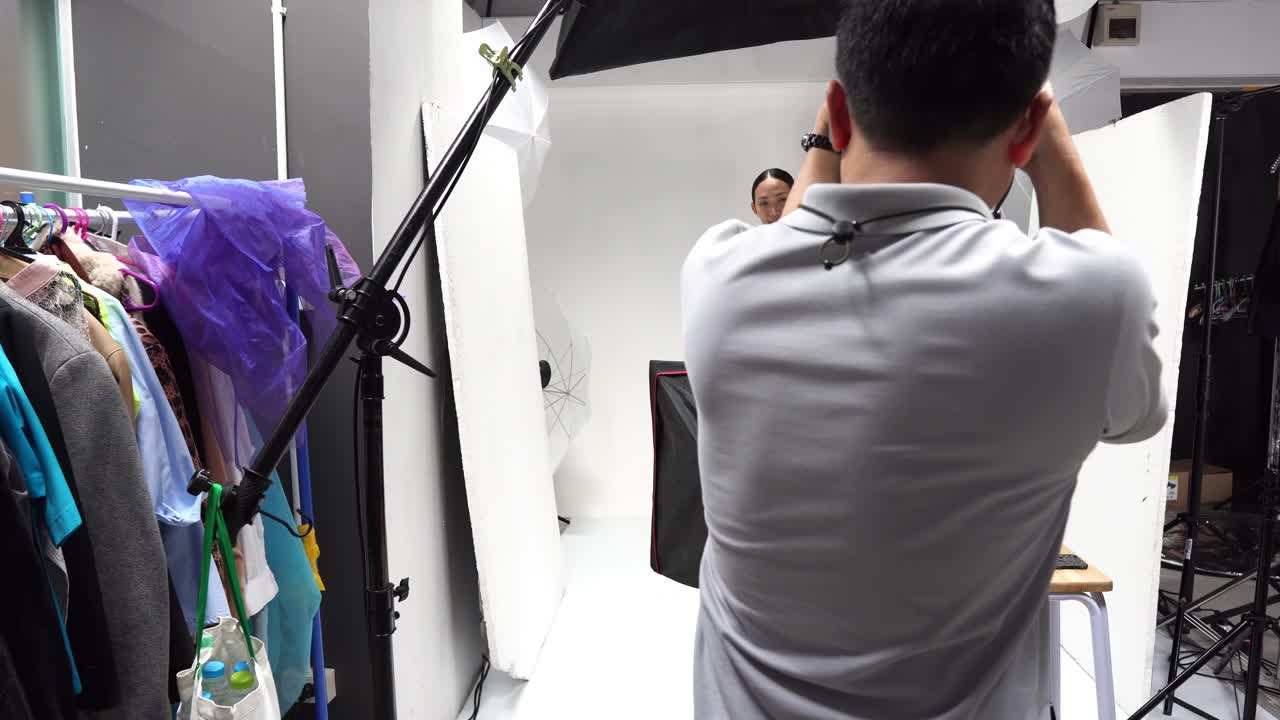 Professional photographer in a studio session with a young Asian model posing in business attire