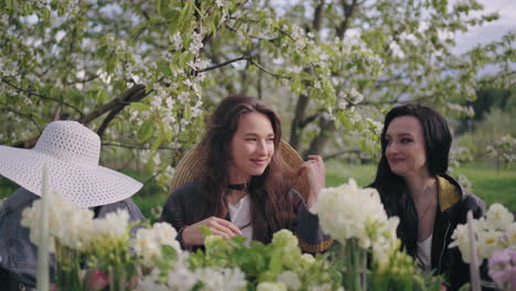 happy women are resting together in garden lunch in blooming orchard in springtime merry ladies