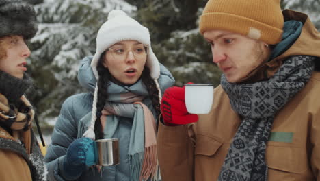 tourists having tea and speaking in winter forest